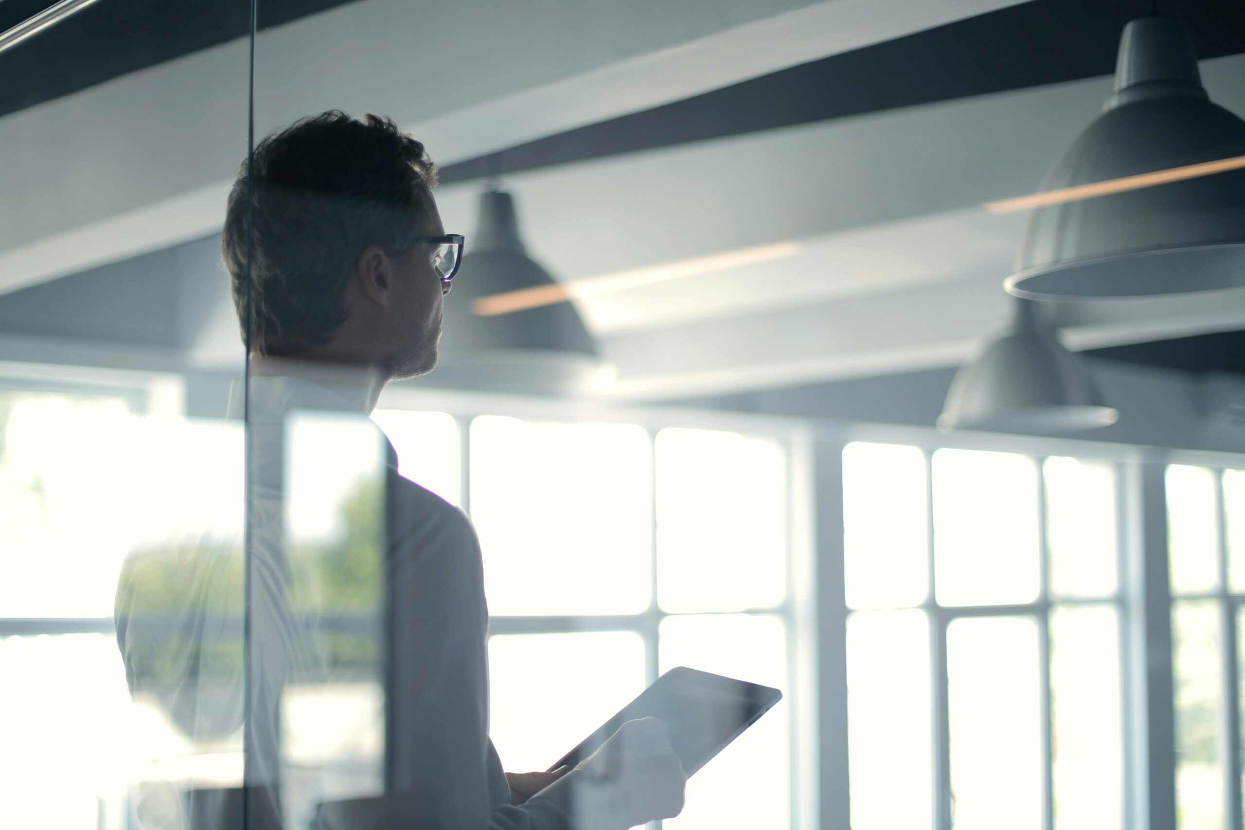 Business professional analyzing strategic data on a tablet, reflecting on critical decisions in a high-level consulting environment.